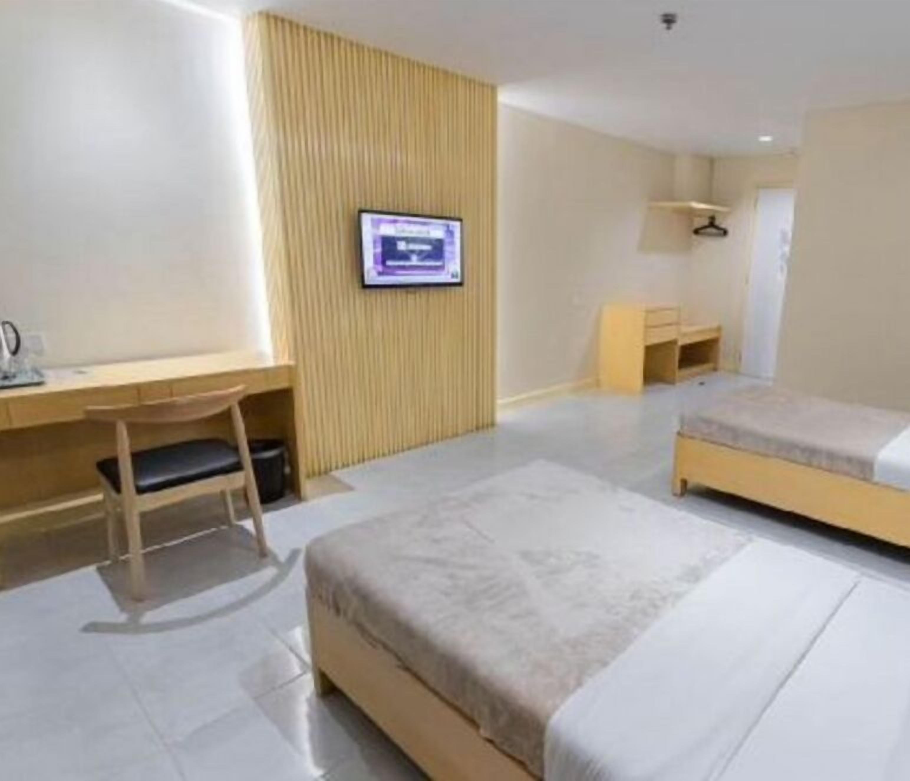 Una camera d'albergo con un letto, una scrivania, una sedia, una televisione e un armadio.