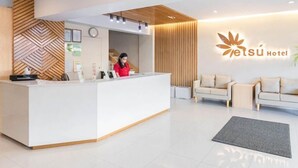A hotel reception area with a modern design, featuring a reception desk, a clock, and a logo on the wall.