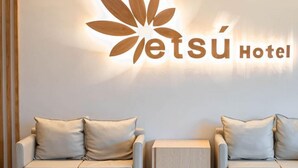 A hotel reception area with a logo and two sofas with cushions.