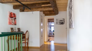 Une pièce spacieuse dotée d’un plancher en bois, d’un escalier avec des rampes vertes et d’œuvres d’art accrochées aux murs.