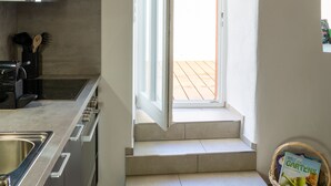 Une cuisine moderne équipée d’une cuisinière intégrée, d’un évier et d’une fenêtre donnant sur une terrasse en bois.