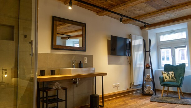 Une salle de bain moderne avec un plafond en bois, un grand miroir, un lavabo et un porte-serviettes.
