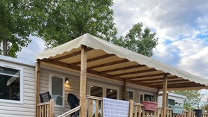 Een houten terras met een overdekte veranda, een trap en potplanten.