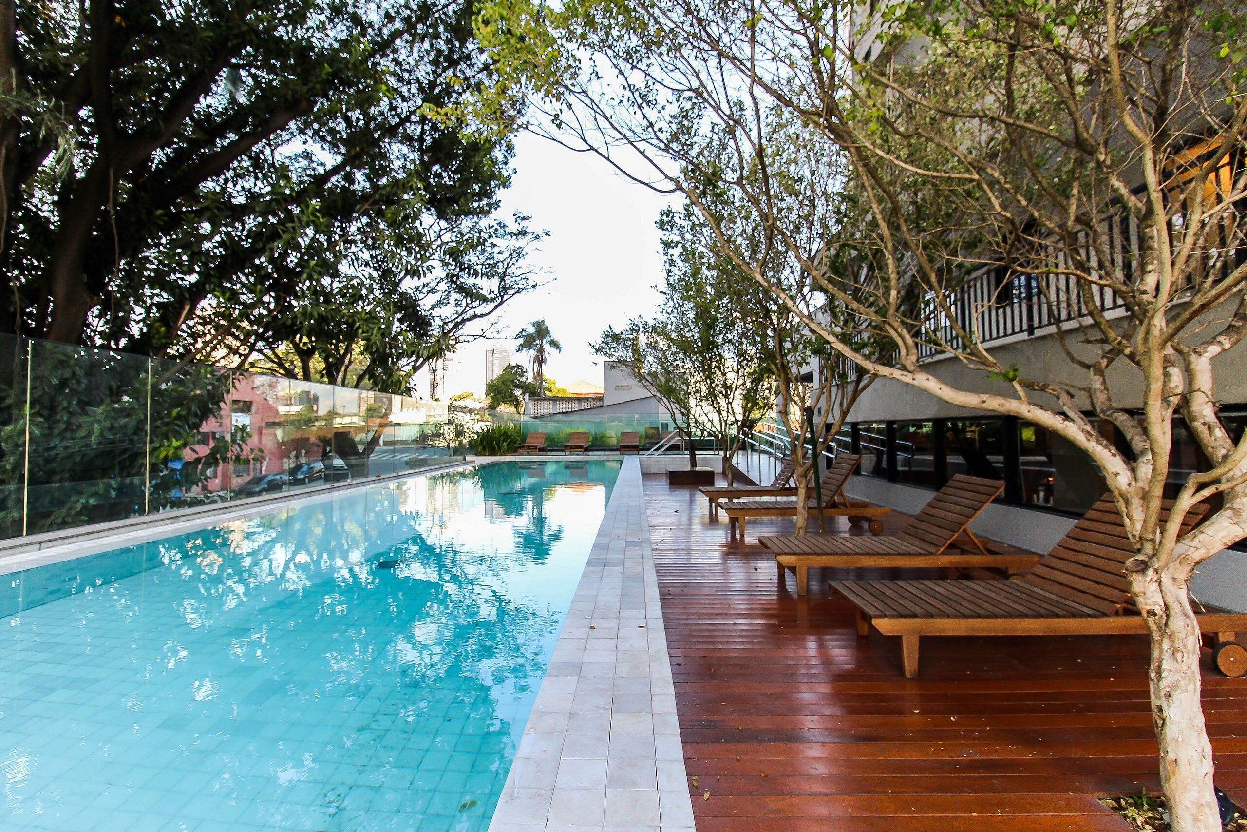 Una piscina al aire libre, sombrillas, sillones reclinables de piscina