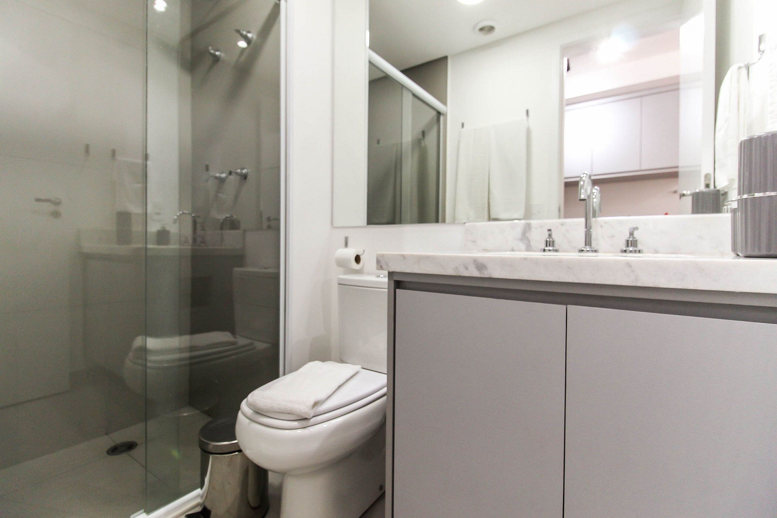 A modern bathroom with a glass shower enclosure, a toilet, and a marble countertop.