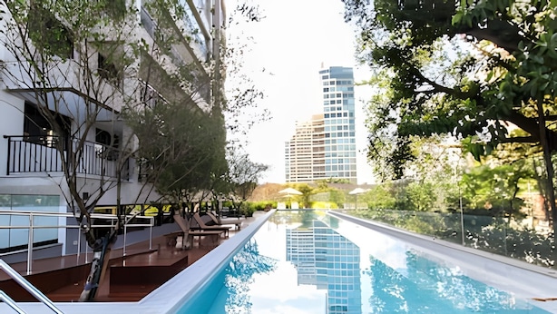 A swimming pool with a clear view of a modern building in the background. - Trends Brooklin (São Paulo)