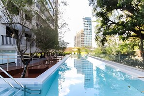 A swimming pool with a clear view of a modern building in the background. - Trends Brooklin (São Paulo)