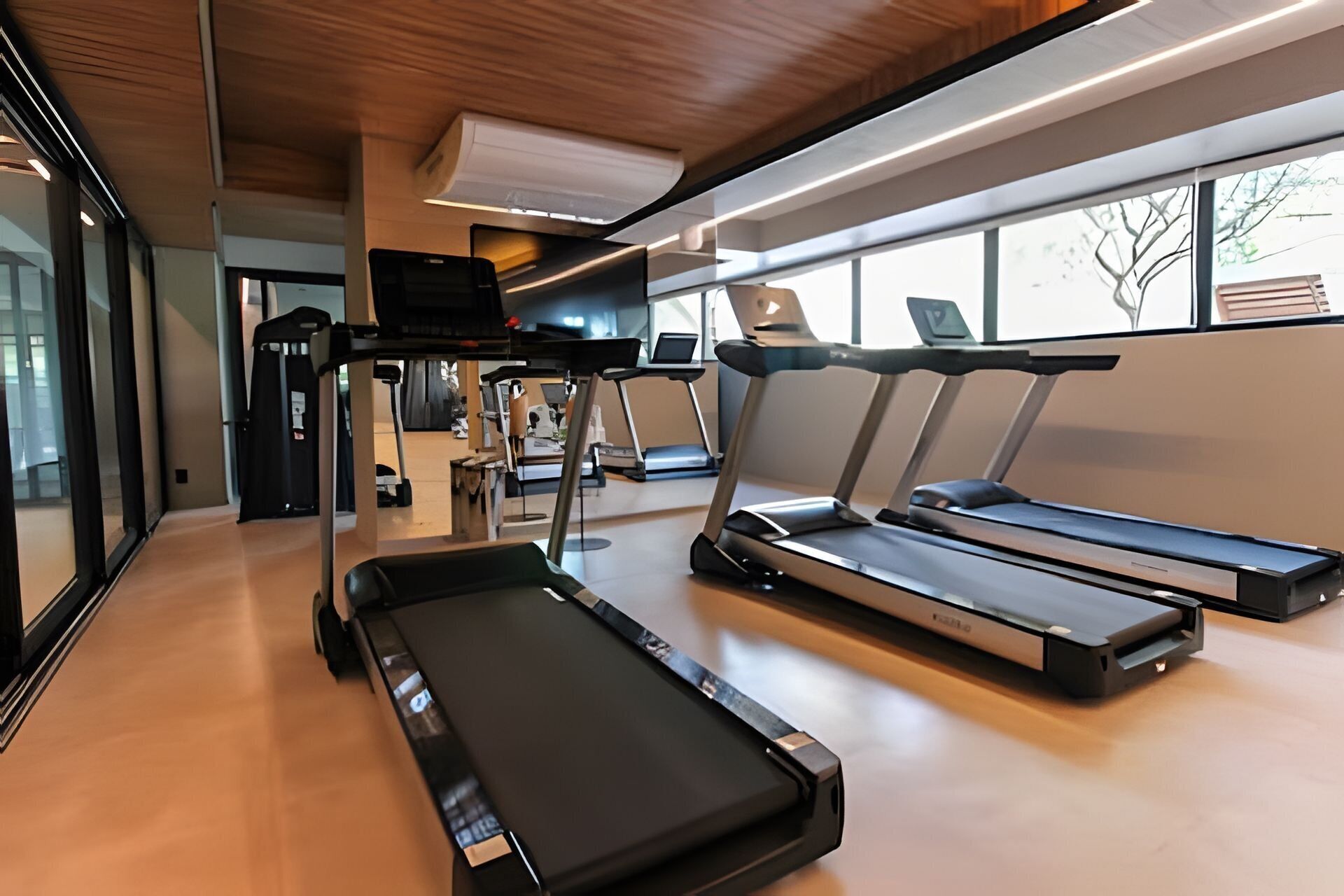 Un gimnasio moderno con cintas de correr, una bicicleta estática y una máquina de remo.