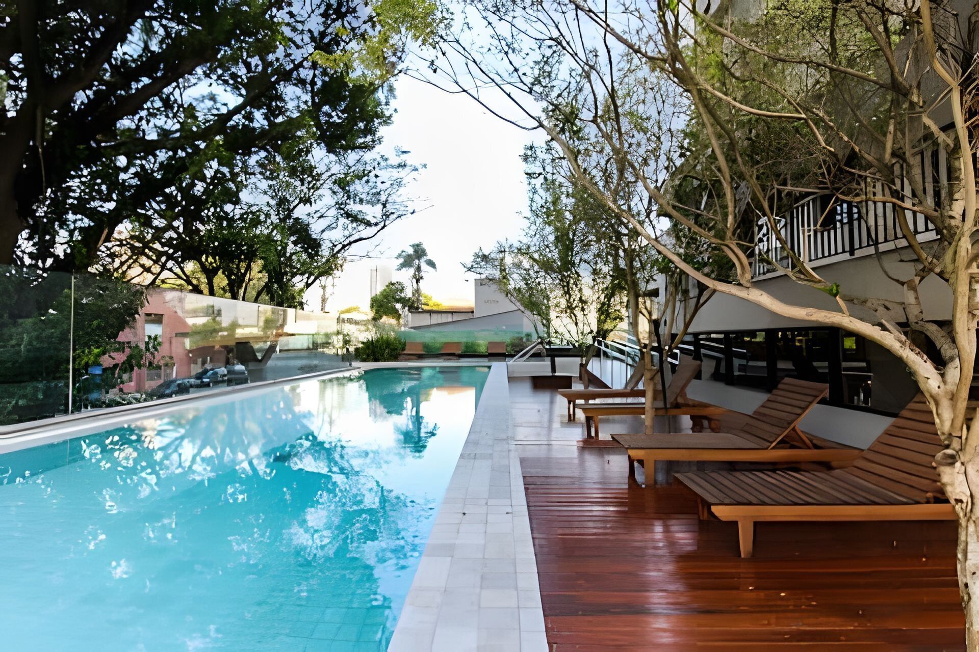 A swimming pool with wooden loungers and a view of a building in the background.