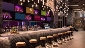 A modern bar area with a long counter, multiple stools, and a variety of bottles on shelves. - Splash into Downtown Miami with tech-led smart stays & sunset drinks by the pool (Miami)