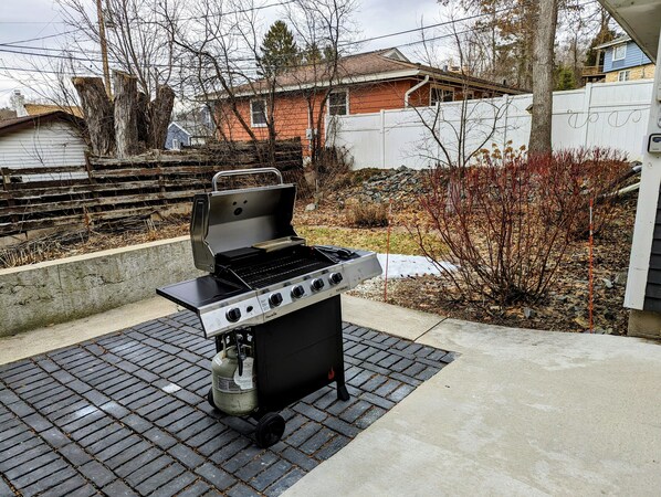 Una parrilla al aire libre con cuatro quemadores, un tanque de gas y una chimenea.