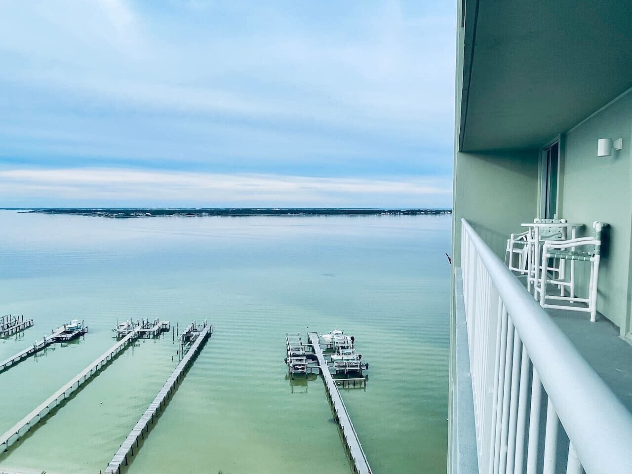 A marina with boats docked, a clear sky, and a balcony with chairs.