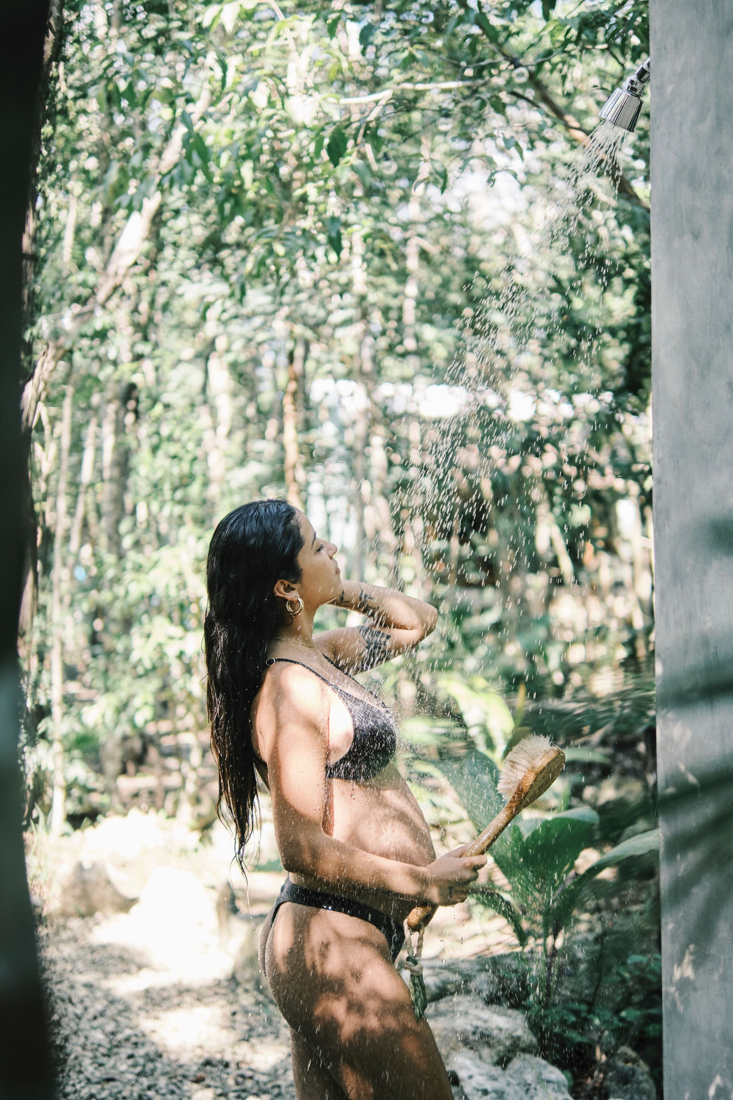 A person in a natural setting with water spraying, surrounded by greenery.
