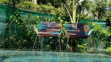 Zona de piscina con dos sillas coloridas y un muro de piedra.