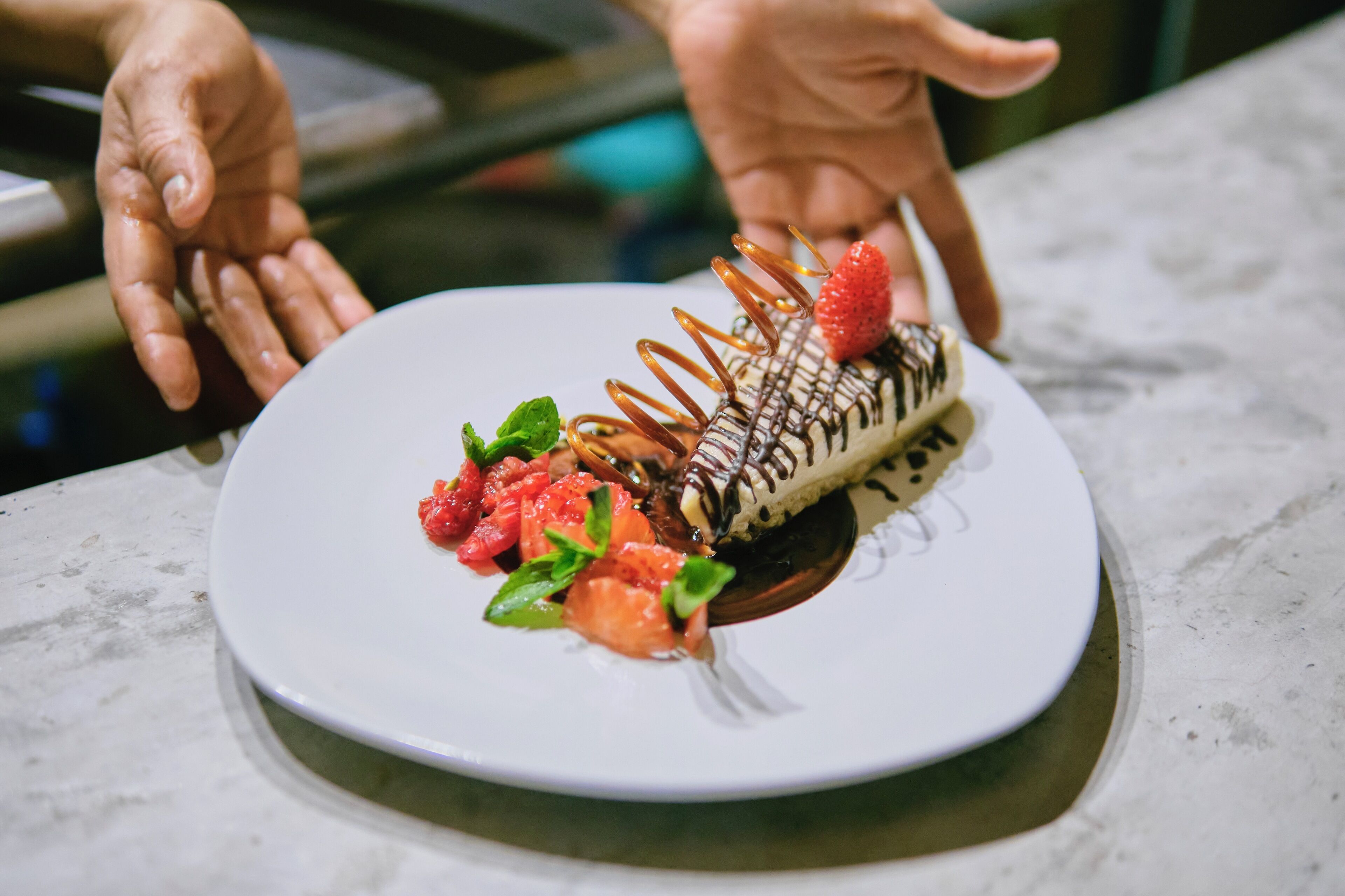 Un postre en un plato blanco con un hilo de chocolate y fresas.