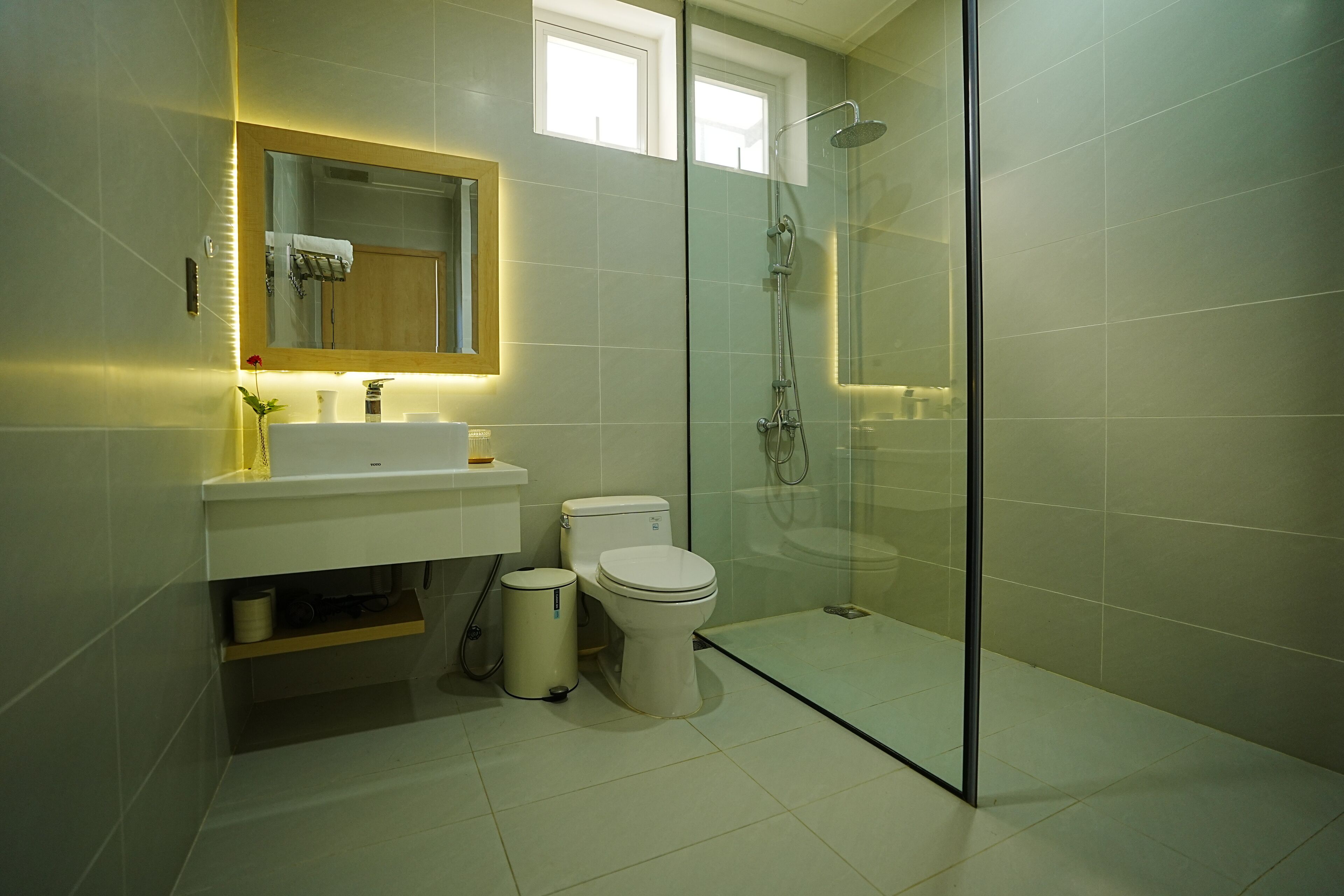 Une salle de bain moderne avec une douche à parois de verre, des toilettes blanches et un meuble-lavabo avec un miroir.