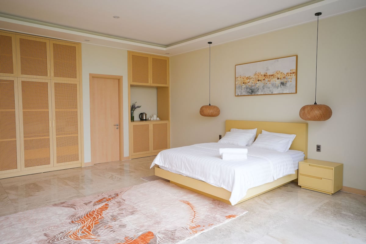 A bedroom with a bed, bedside tables, a wardrobe, and a painting on the wall.