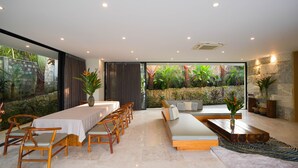 A modern dining area with a long table and chairs, a sofa, and a coffee table. - Kiwuki Luxury Villa  (Phu Quoc)