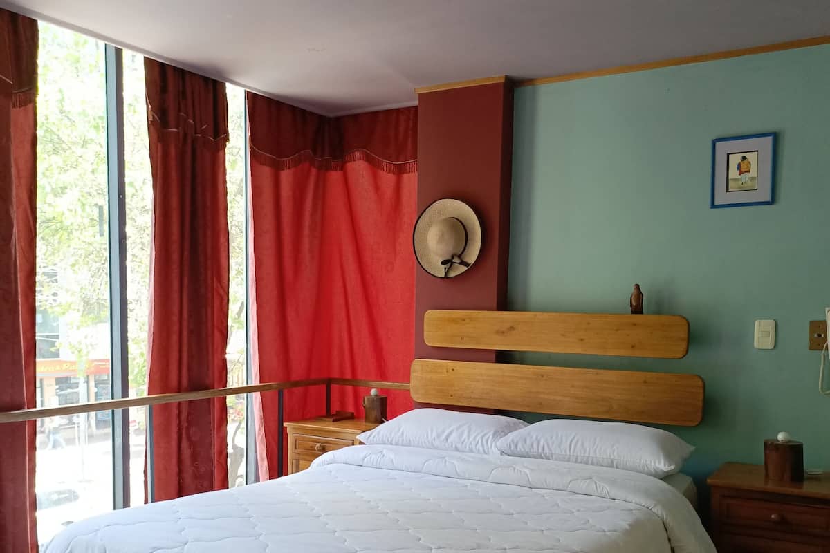 A neatly made bed with white bedding, a wooden headboard, and a nightstand with a lamp.