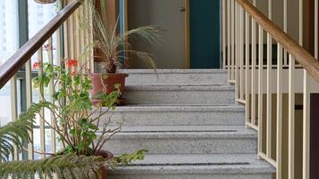 A staircase with potted plants, a door with a sign, and a handrail.