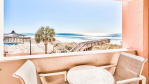 Un balcón con vista a la playa, una piscina y una terraza de madera.