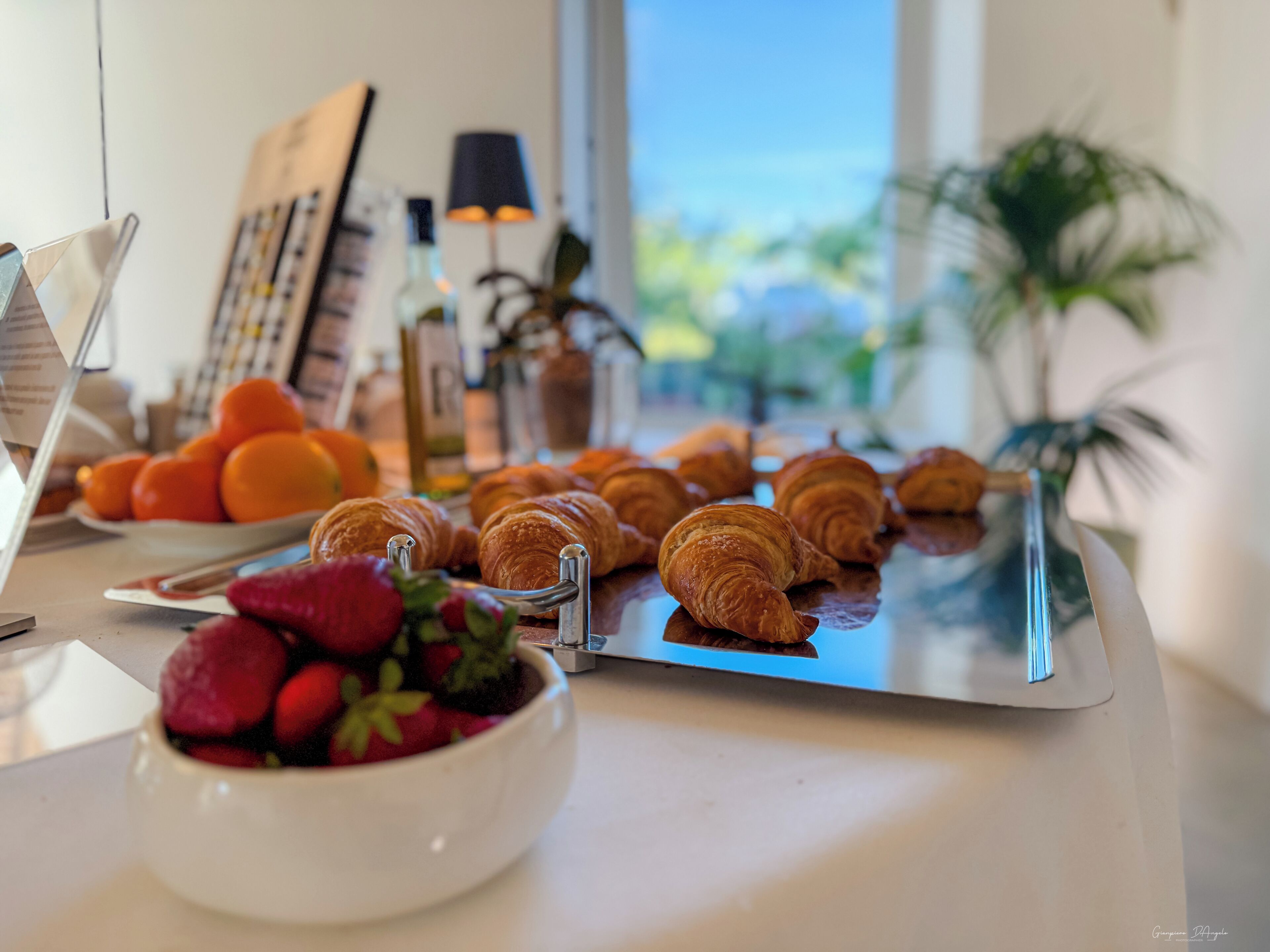 Un bufé de desayuno con cruasanes, fresas y naranjas.