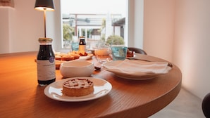 A dining table with a bottle of wine, a plate with a pastry, a bowl, and a glass of water. - Molikè Country House  (Giulianova)
