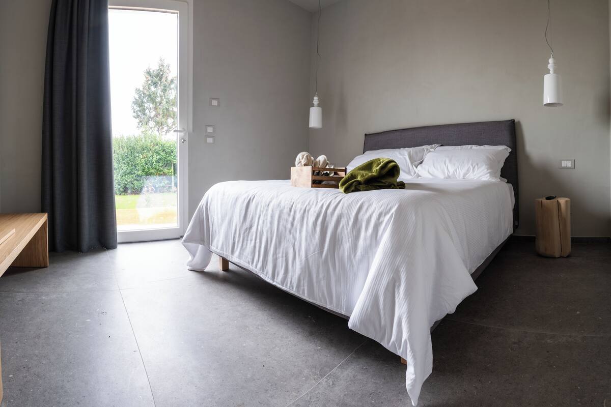 A bedroom with a bed, bedside table, and a bench.