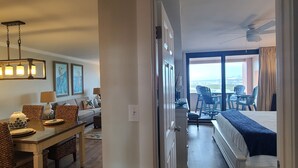 A hotel room with a bed, a dining area with a table and chairs, and a view of the outdoors. - Beautifully Decorated Beach Front at Jetty East! One FREE Beach Chair Setup Dail (Destin)