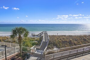 A wooden boardwalk leading to a beach with a clear view of the ocean.