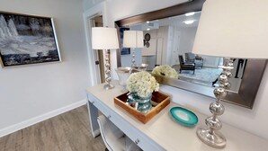 A bathroom vanity with a mirror, a framed picture, and decorative items including a vase of flowers and a teal soap dish. - Best views of the Gulf of Mexico and the Jetties. One free beach chair set up da (Destin)