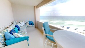 A balcony with a sofa and chairs, overlooking a beach with umbrellas. - Best views of the Gulf of Mexico and the Jetties. One free beach chair set up da (Destin)