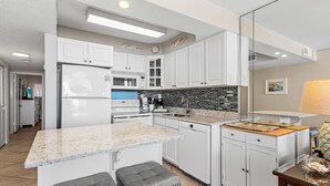 Eine moderne Küche mit weißen Schränken, einer Arbeitsplatte aus Granit und einem eingebauten Backofen.