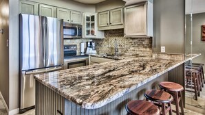 Eine moderne Küche mit einer Granit Arbeitsplatte, Edelstahlgeräten und Holzbarhocker.