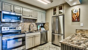 Una cocina moderna con electrodomésticos de acero inoxidable, encimera de granito y salpicadero de azulejos estampados.