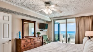 A hotel room with a large bed, a wooden dresser, a television, and a balcony with a view of the ocean. - Gulf view unit at Jetty East! One beach chair set up daily. (Destin)