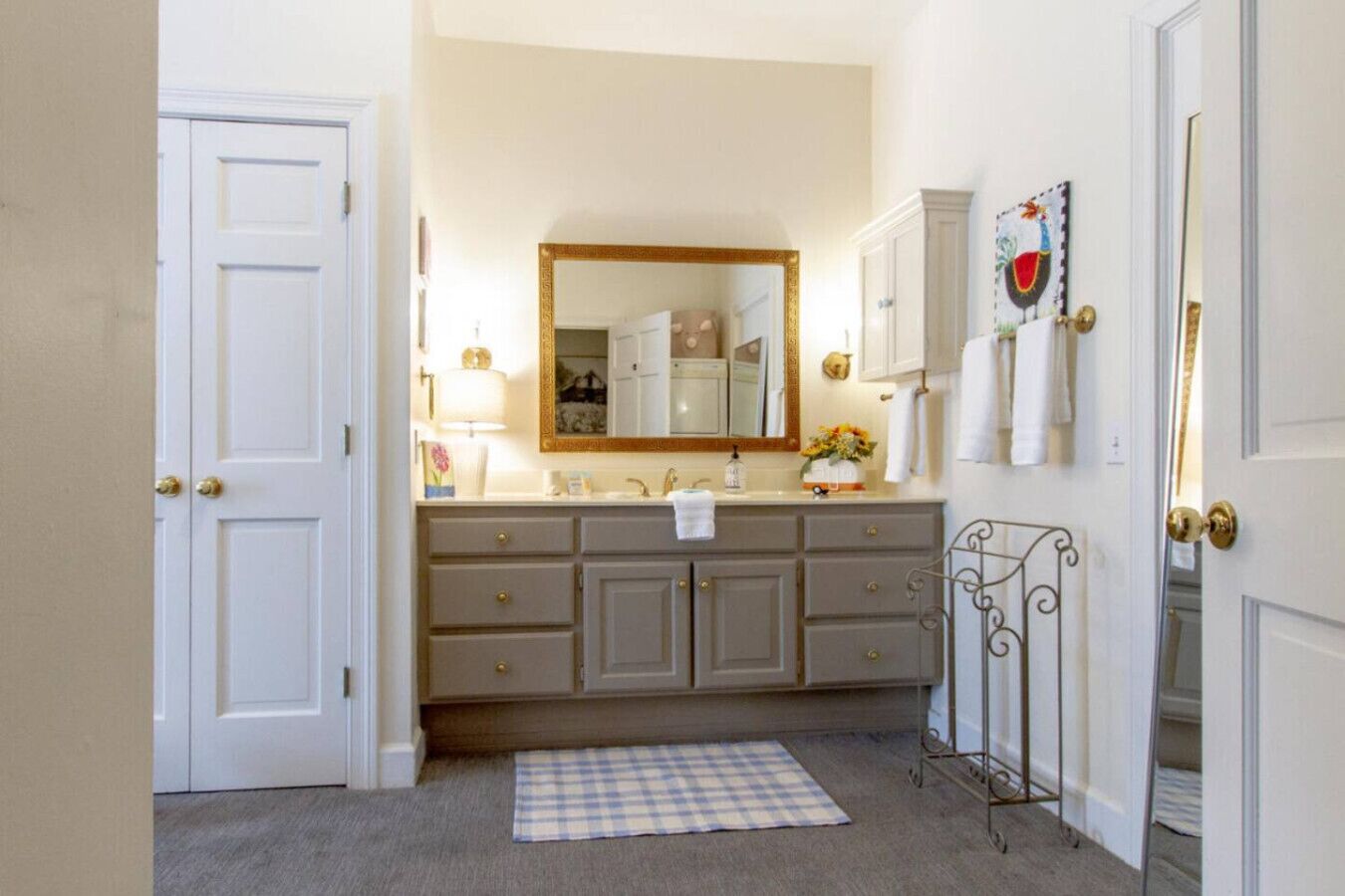 A bathroom with a double vanity, a large mirror, and a towel rack.
