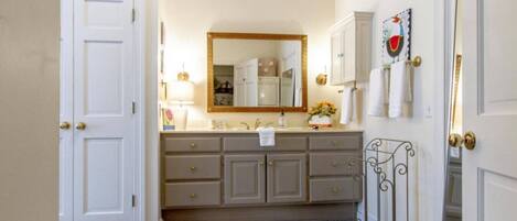 A bathroom with a double vanity, a large mirror, and a towel rack.