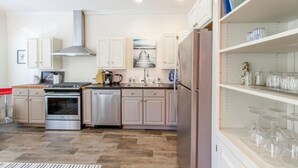 Een moderne keuken met roestvrijstalen apparatuur, witte kastjes en een ingebouwde wijnrek.