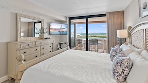 A hotel room with a large bed, a dresser, a television, and a balcony with a view of the ocean. - Jetty view at Jetty East! One beach chair set up daily. (Destin)