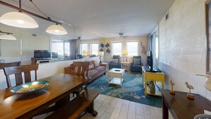 A spacious living area with a wooden dining table, comfortable seating, and a view of the outdoors.