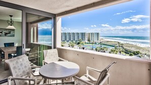 Ein Balkon mit Blick auf Strand und Meer, ausgestattet mit Stühlen und einem Tisch.