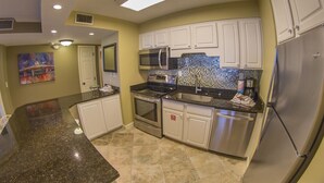 A modern kitchen with white cabinets, stainless steel appliances, and a tiled backsplash.