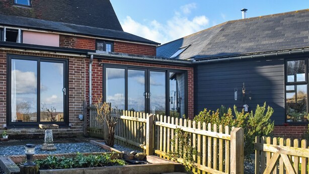 A house with a brick facade, large windows, and a wooden fence. - 2 bedroom accommodation in Shotley, Ipswich (Shotley, Ipswich)