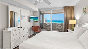 A hotel room with a bed, a dresser, a chair, a TV, a balcony with a view of the ocean, and a ceiling fan. - Spacious three-bedroom unit! One free beach chair set up daily. (Destin)