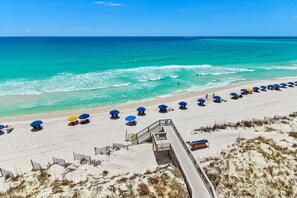 A beach with a wooden boardwalk leading to a sandy shore, lined with blue and yellow umbrellas. - Gulf View deluxe Condo at Jetty East! Enjoy one free beach chair set up and umbr (Destin)