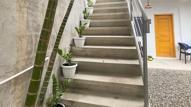 A concrete staircase with potted plants on the sides, leading to a wooden door. - Sunset Paradise Moaboal (Moalboal)
