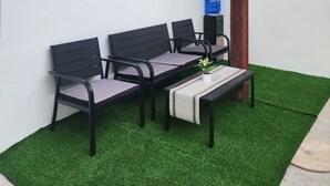 A seating area with two black chairs and a bench, a small table with a plant, and a ceiling light fixture. - Sunset Paradise Moaboal (Moalboal)