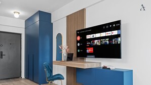 En moderne stue med et fladskærms-tv på væggen, der viser en streamingtjenestes brugerflade.