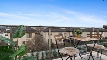 Enjoy the view from this balcony with a table, chairs, and a potted plant.